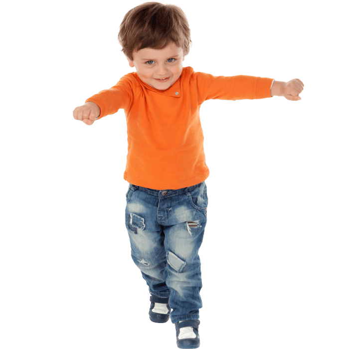 Blije jonge jongen in oranje shirt en jeans die springt en lacht.